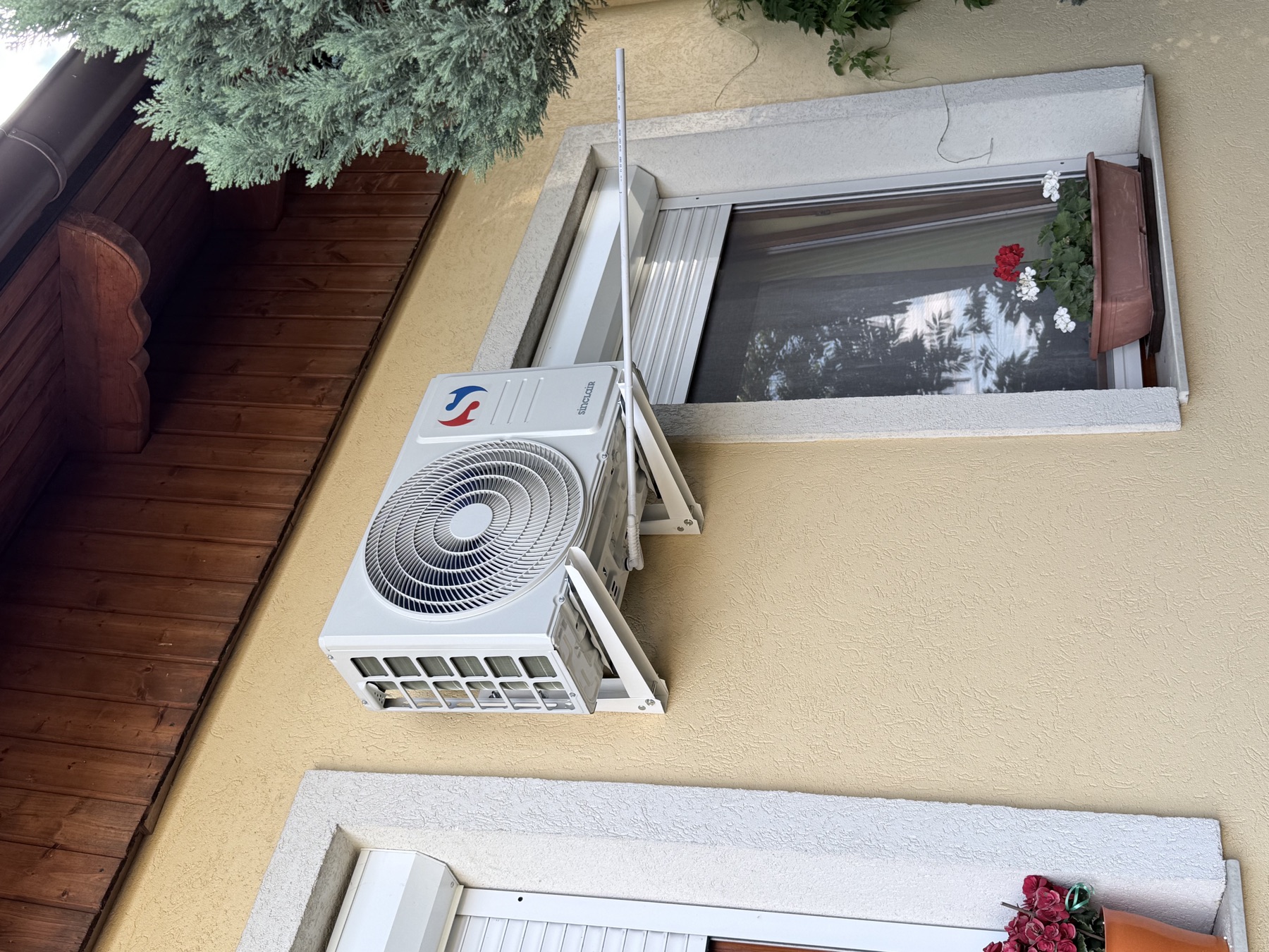 Klíma kültéri egysége családi ház homlokzatán, ablak mellett